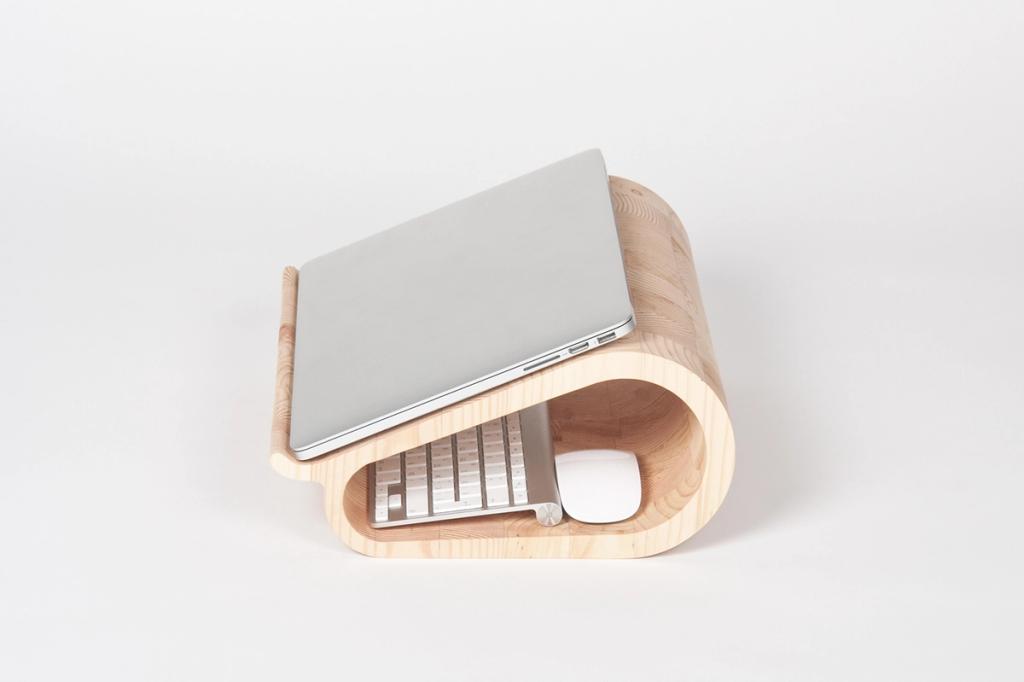A cocoon-shaped wooden laptop stand with a recessed area for the keyboard and mouse, designed by Lyosha Galkin