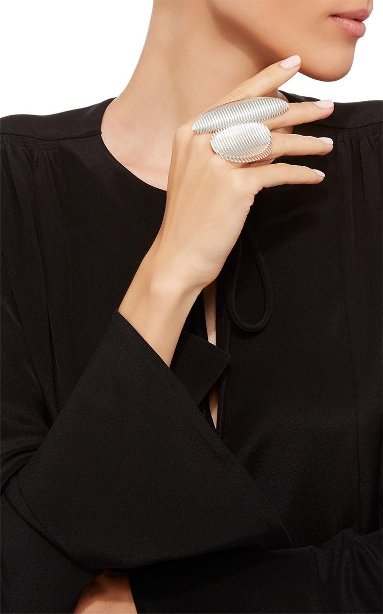 A large silver ridged ring on the finger of a model in a black dress