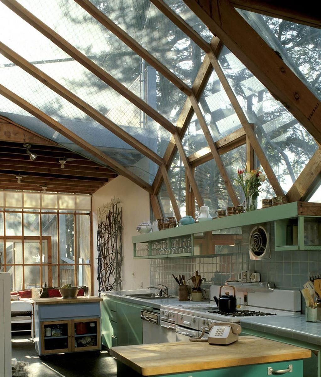 The kitchen of Gehry's house beneath a glass canopy supported by wooden beams, with chain-link fencing