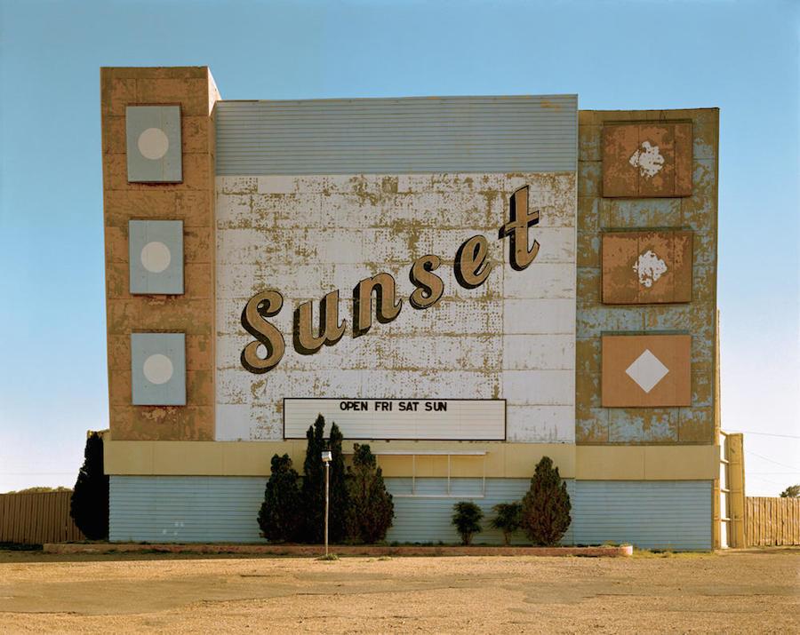 The faded marquee sign of the Sunset drive-in cinema against a clear blue sky