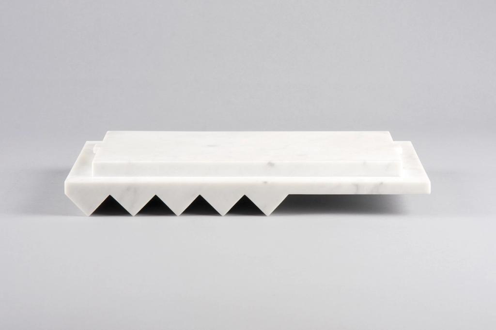 A white marble tray with a serrated triangular base against a grey background, designed by Lyosha Galkin