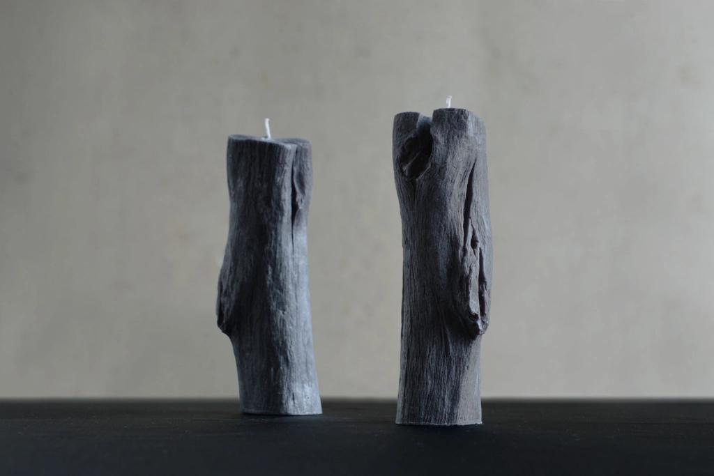 Two grey candles shaped like charred tree trunks