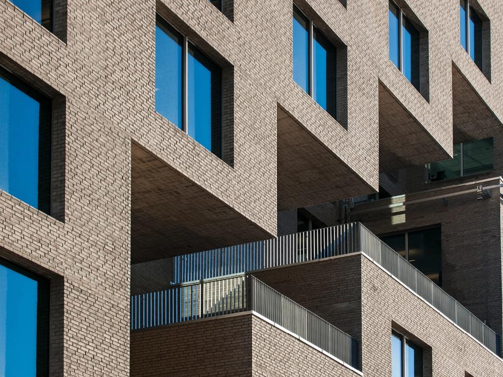 The brick facade of a building in the Barcode district with deep window recesses and a balcony