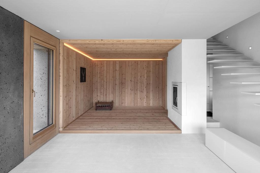An interior with wooden walls, a fireplace and a floating concrete staircase