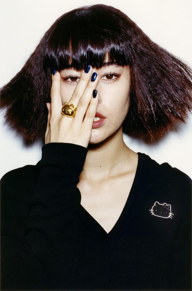Portrait of a girl wearing a gold Hello Kitty ring and a patch on a black jumper