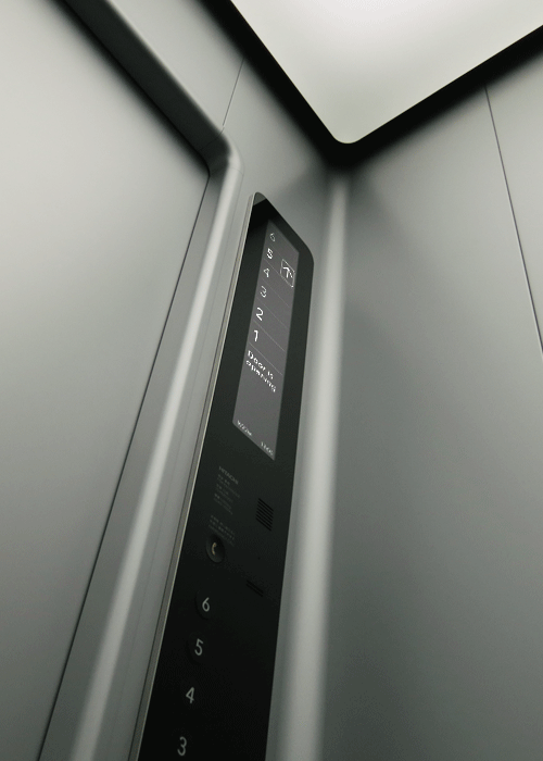 Minimalist lift interior with grey panels and a narrow control panel