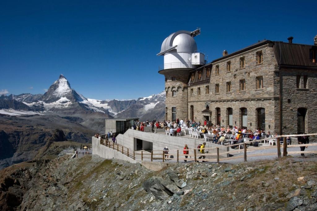 The terrace of Kulmhotel Gornergrat with guests, the Matterhorn peak close by on a summer's day