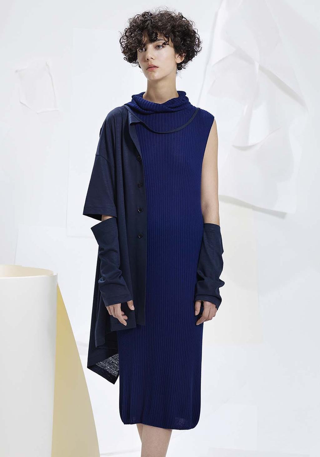 A model in a dark navy ribbed dress with a shirt draped over the shoulders and fingerless gloves