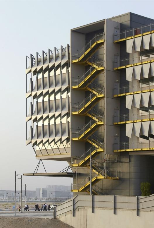 A Masdar City building with solar shading louvres and yellow external staircases in the desert