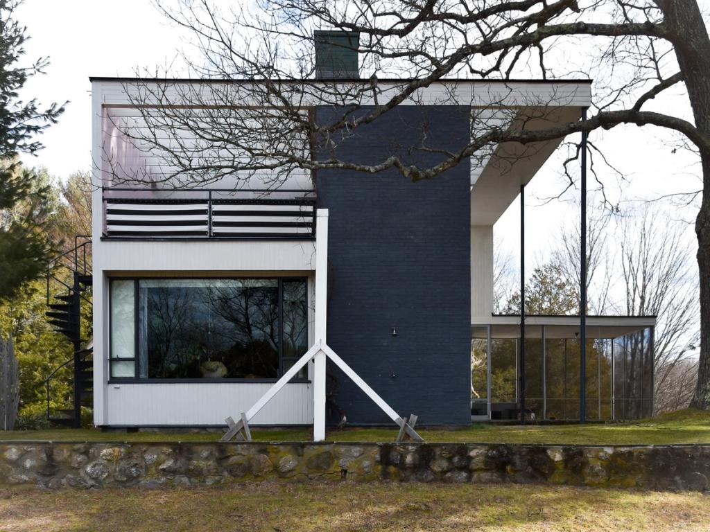 The side façade of Gropius House with a dark chimney stack, ribbon window and external spiral staircase