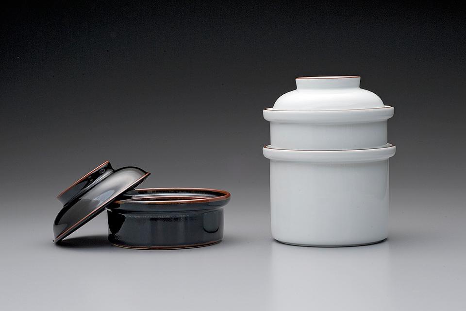 White porcelain container with a lid and a dark bowl with its lid ajar