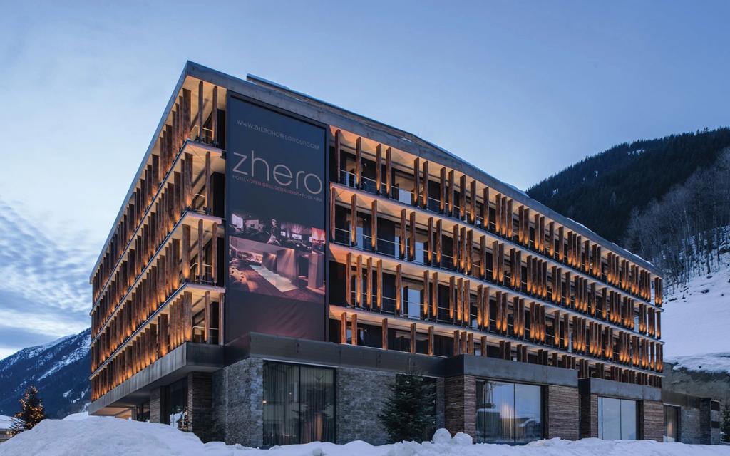 The illuminated façade of Hotel Zhero with its timber slats in the winter dusk