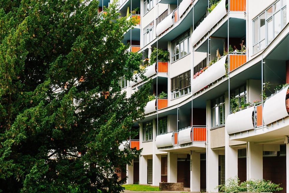 The Interbau residential building with curved balconies and orange railings, seen behind a tree