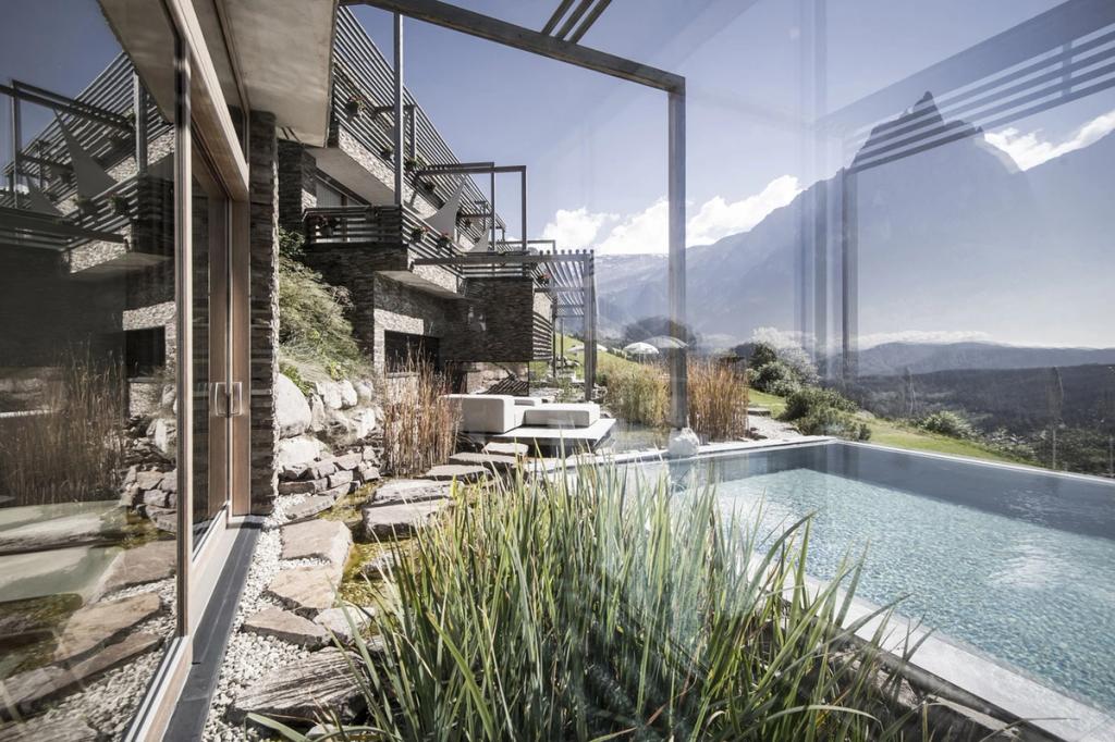 An infinity pool beside the hotel, framed by stone walls and views of the mountain peaks