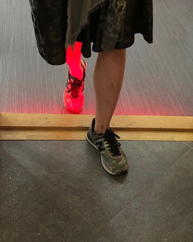 Feet in trainers on the floor, one foot lit by a red glow