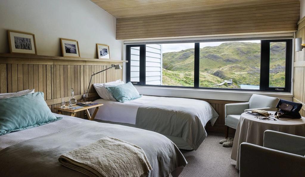 A twin room with a view of the green hills of the Patagonian nature reserve