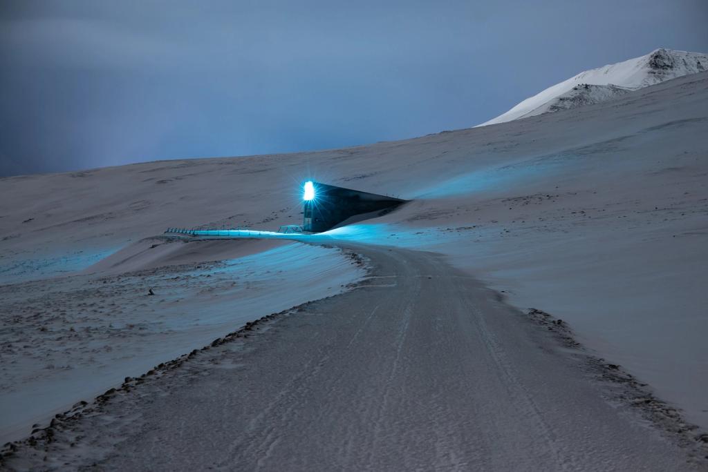 The illuminated installation above the vault entrance glowing at dusk on a snow-covered mountain slope