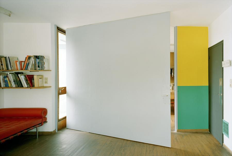 An apartment in the Unité d'Habitation in Marseille, with a red sofa and a yellow-green panel