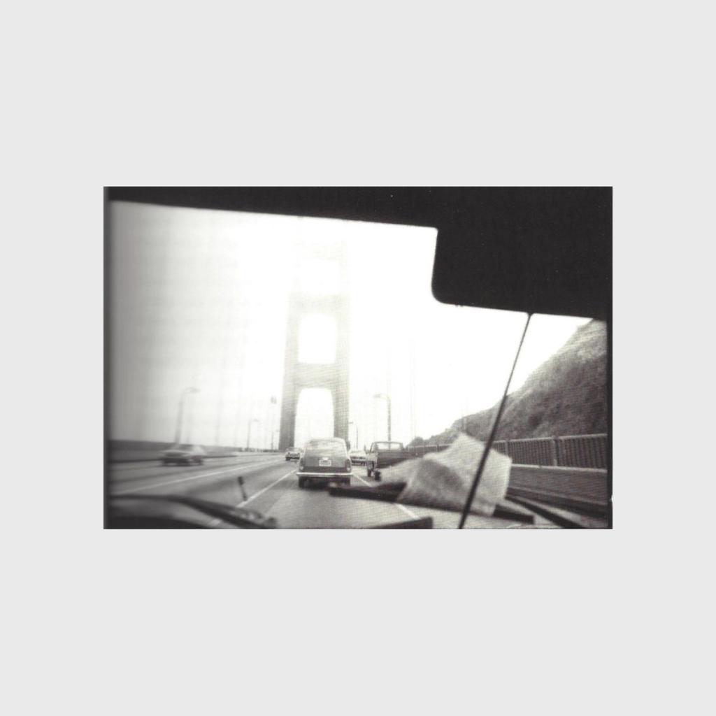 A black-and-white photograph of the Golden Gate Bridge seen through a car windshield