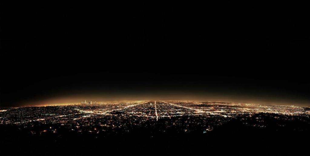 A nocturnal cityscape panorama, lights stretching to the horizon beneath a black sky