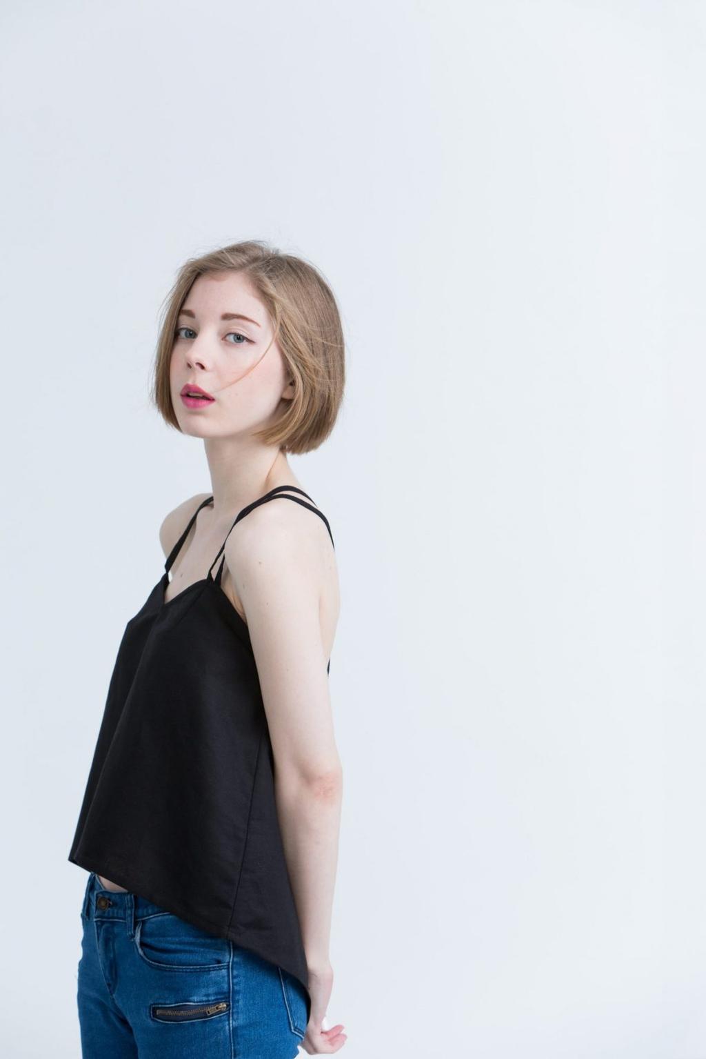 A model in profile wearing a black Kestan slip top with thin straps and blue jeans