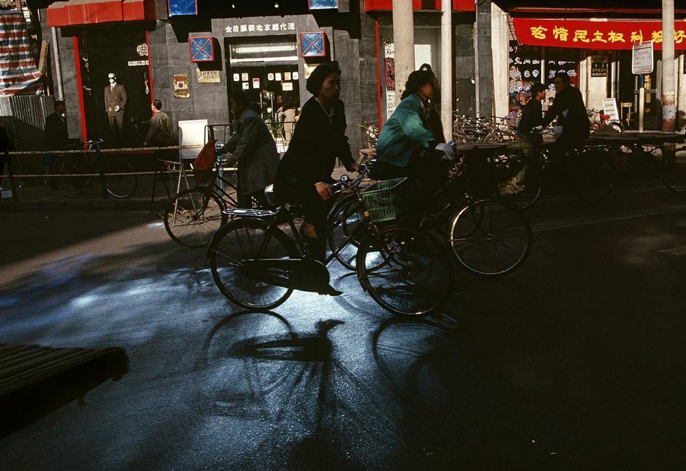 Cyclists on a dark city street in China, a shaft of light on the asphalt