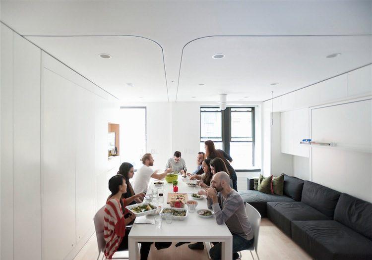 Группа людей за общим обедом в белой студии квартиры LifeEdited