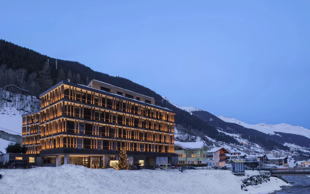 The illuminated Hotel Zhero building in the evening, set among a snow-covered Alpine village