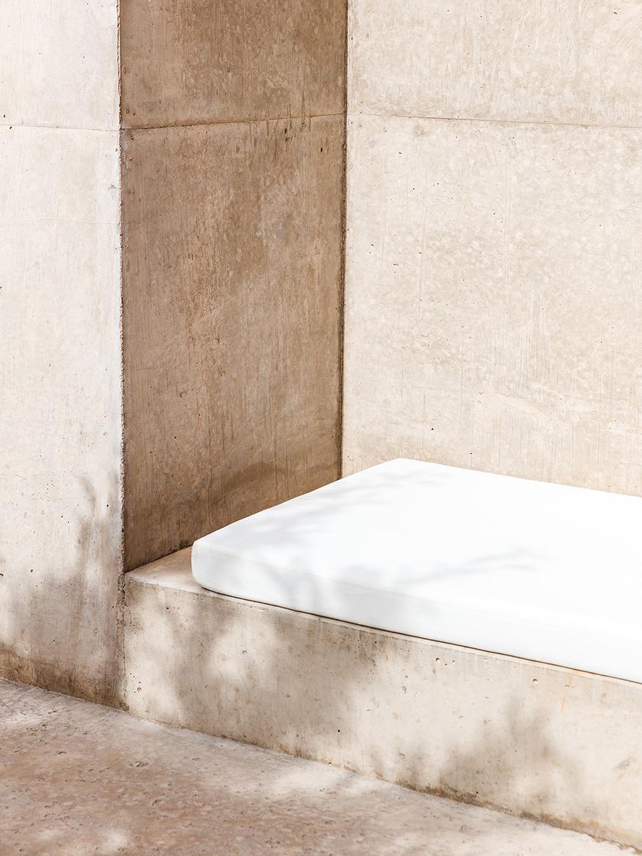 A concrete alcove with a white upholstered bench and the play of sunlight and shadow at Amangiri