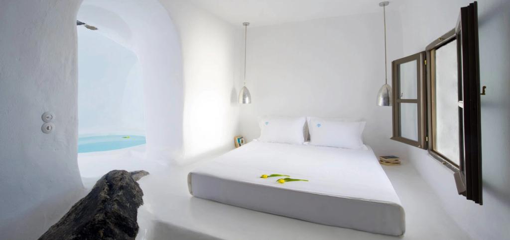 Белая спальня-пещера Sophia Suites с проёмом, ведущим к небольшому бассейну