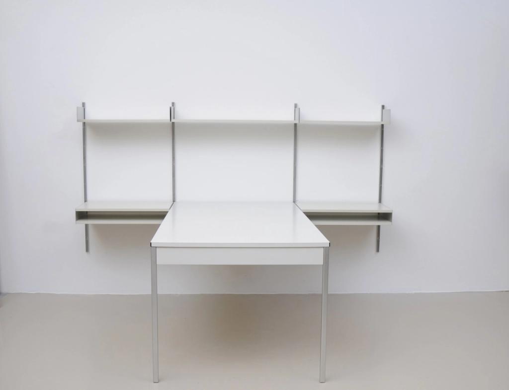 Vitsoe 606 wall system with shelves on vertical rails and an attached white desk