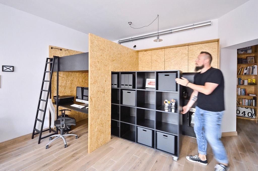 Мужчина двигает перегородку из OSB, открывая кухню и рабочее место