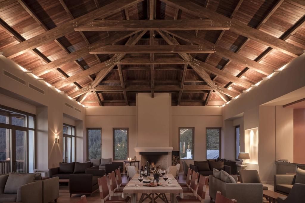 A lounge with a high timber rafter ceiling and a set dining table