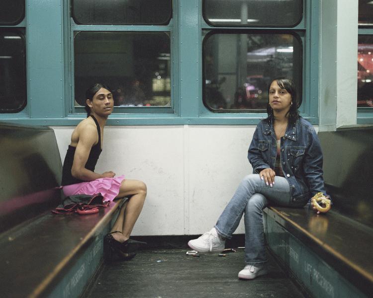 Two passengers sitting across from each other on benches in a night-time metro carriage