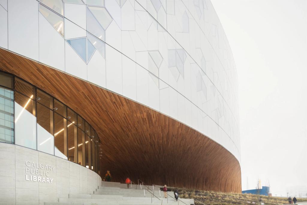The curved facade of the Calgary library with a wooden arch above the entrance and the inscription Calgary Public Library