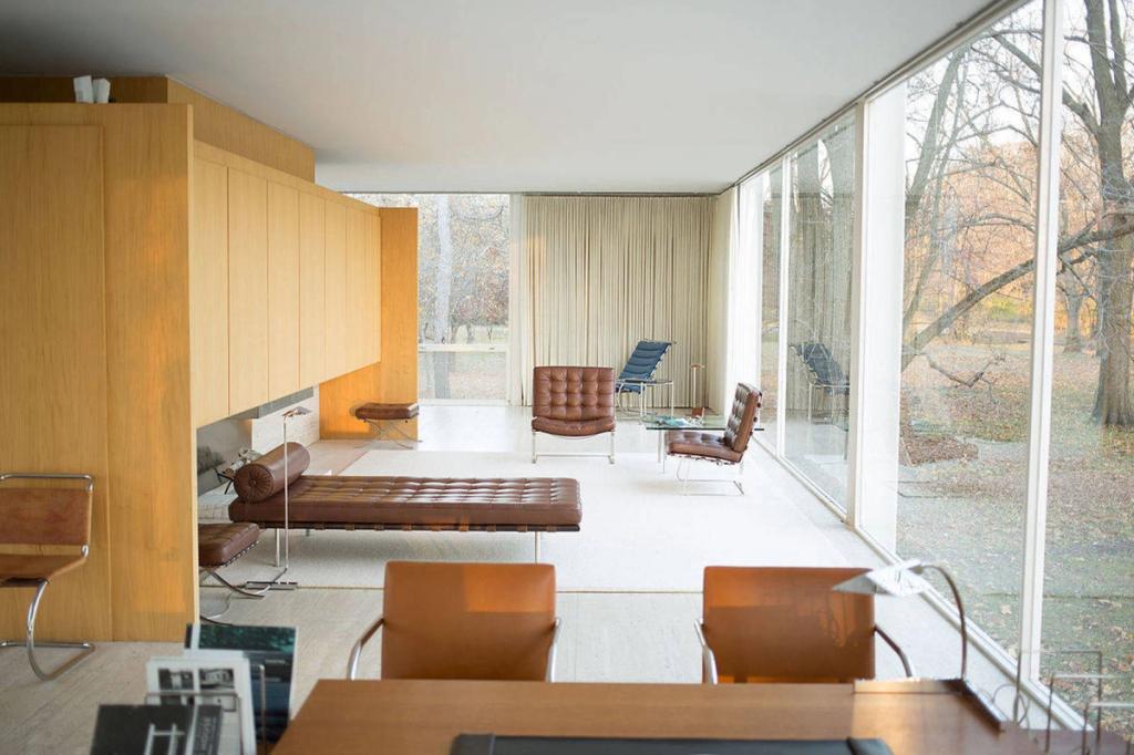 Living area of the Farnsworth House with a leather daybed, Barcelona chairs, and glass walls