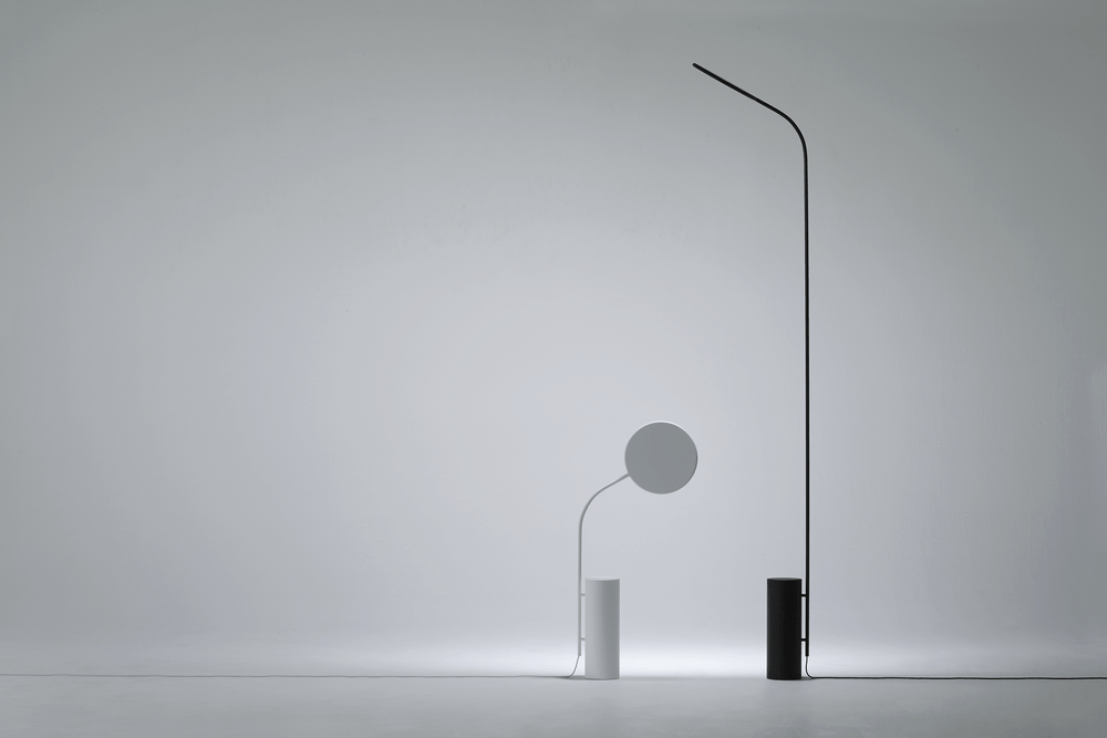Two minimalist floor lamps: a low disc lamp and a tall curved one