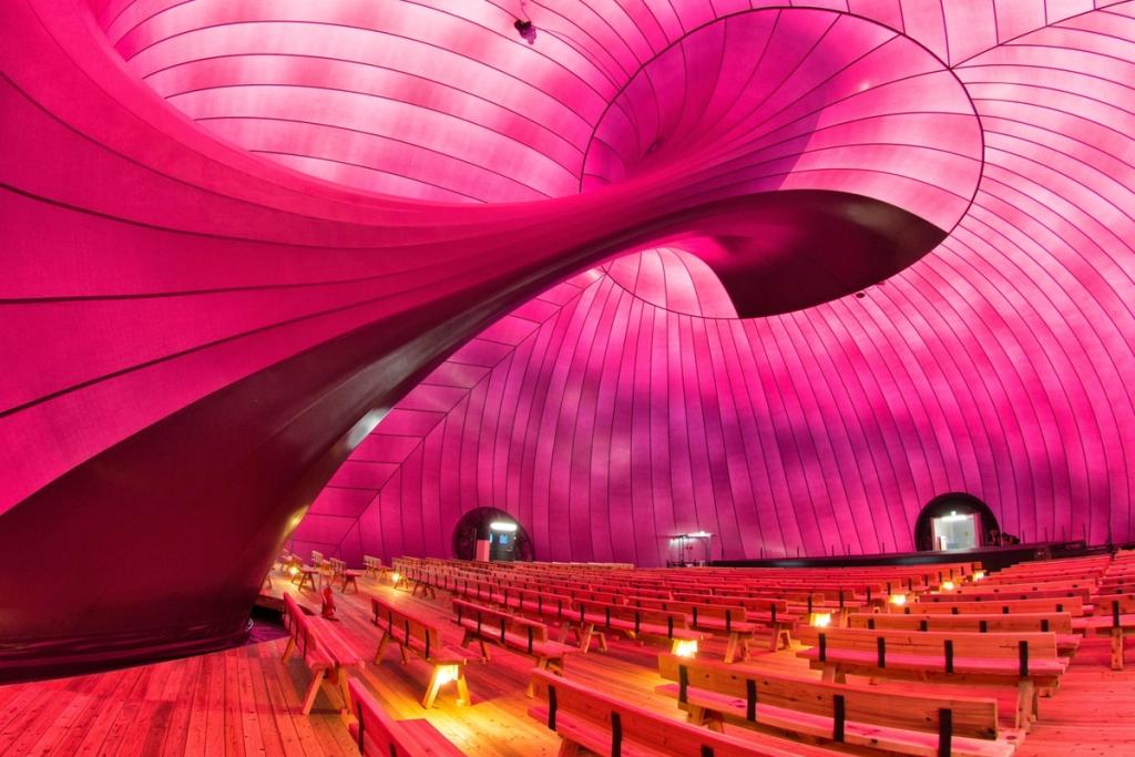 The interior of Ark Nova, with its vivid pink inflatable shell and wooden auditorium benches