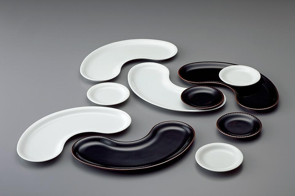 A set of white-and-black porcelain dishes in a curved, bean-like shape