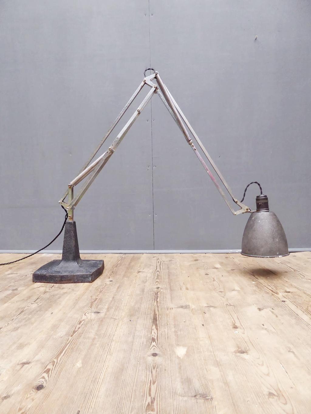 Старая лампа Anglepoise с облезшим окрашенным корпусом рядом с вазой сухоцветов на столе