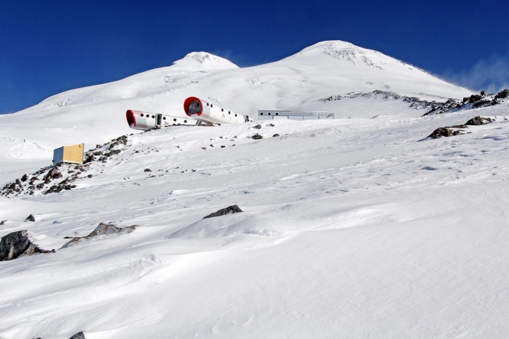 Капсульный отель LeapRus на снежном склоне Эльбруса на фоне двух вершин