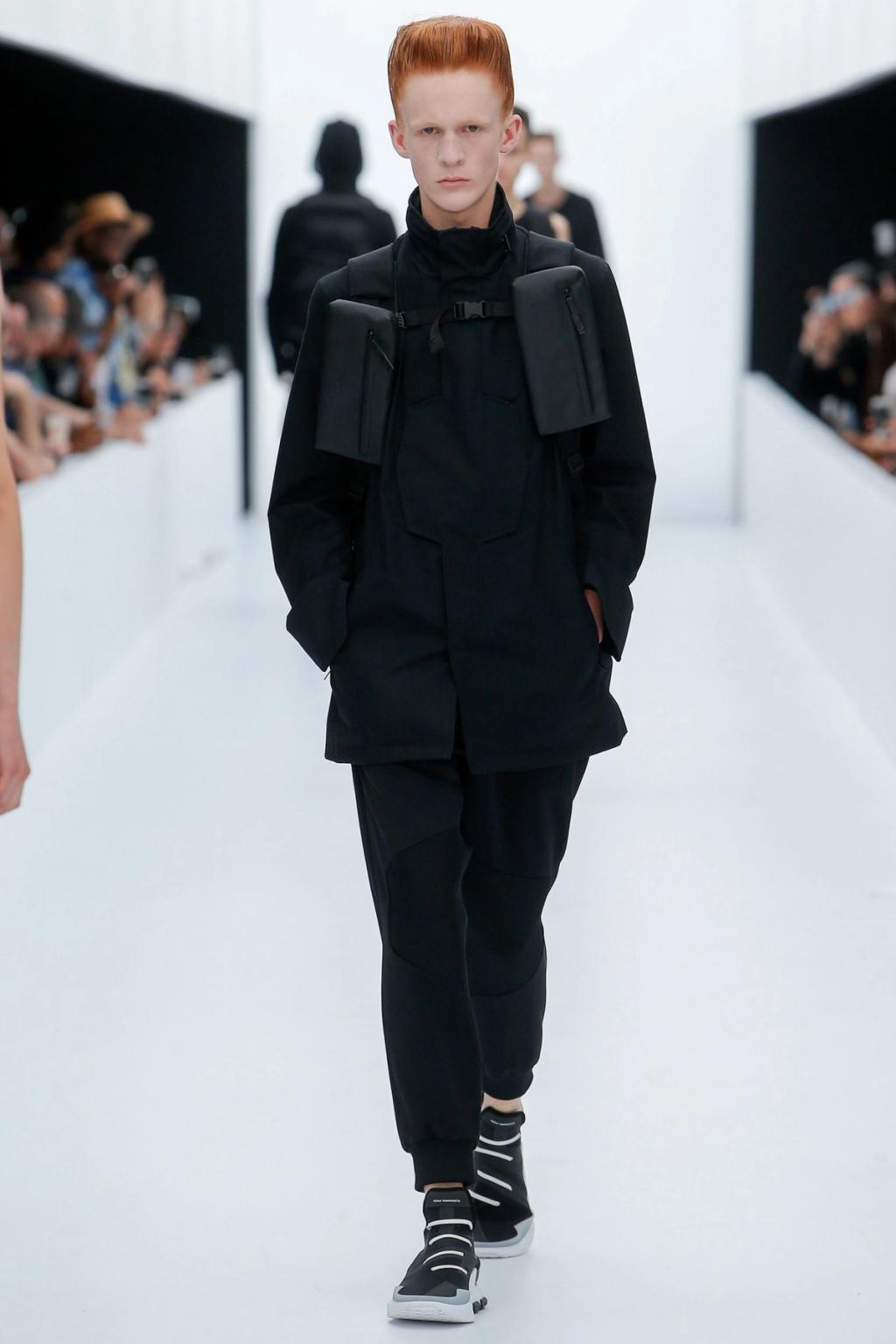 A Y-3 model in black clothing and a technical jacket on the runway