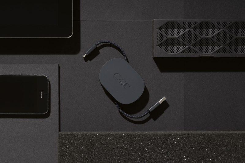 The dark ONE charging device with two braided cables amid black electronics, designed by Katerina Kopytina