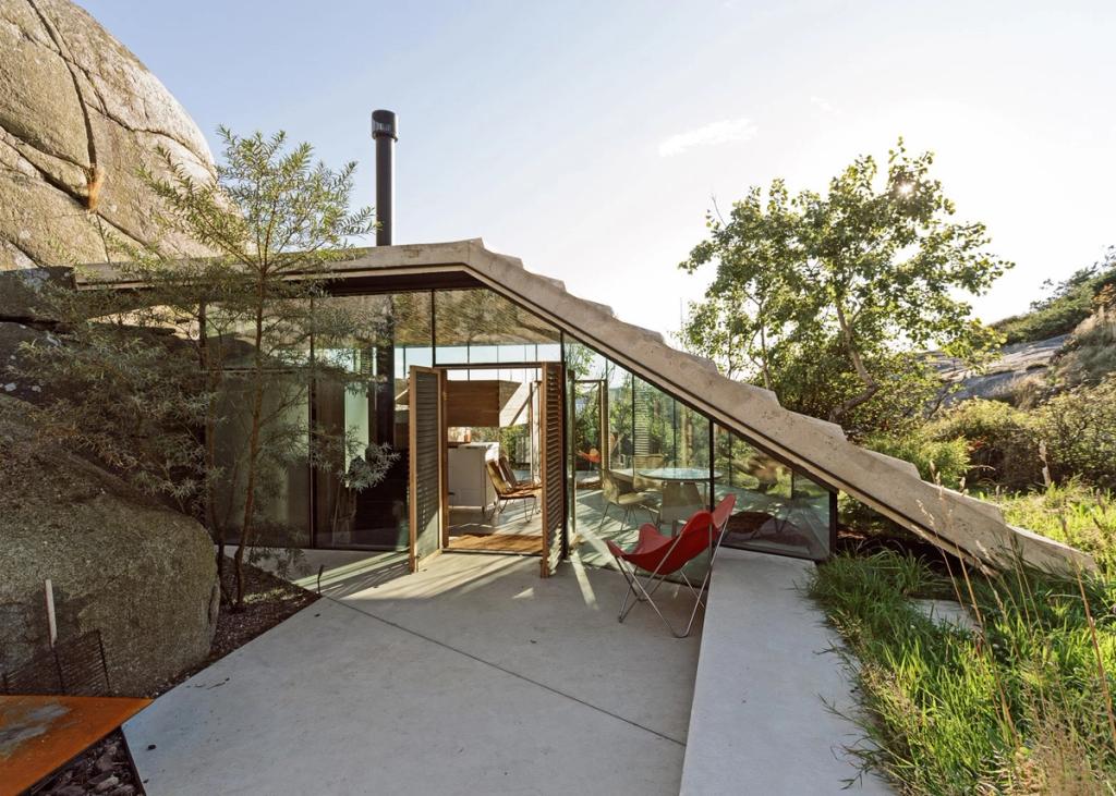 The terrace of a coastal cabin with sliding glass walls beneath an angled concrete roof