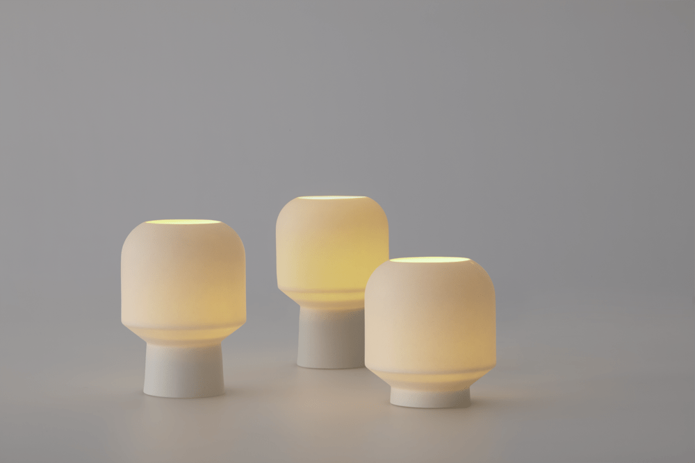 Three white table lamps emitting a warm glow at the top