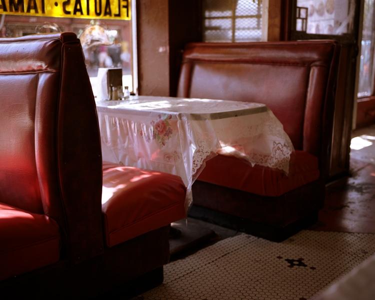 Red leather sofas and a table with a lace tablecloth by the window of a Mexican diner
