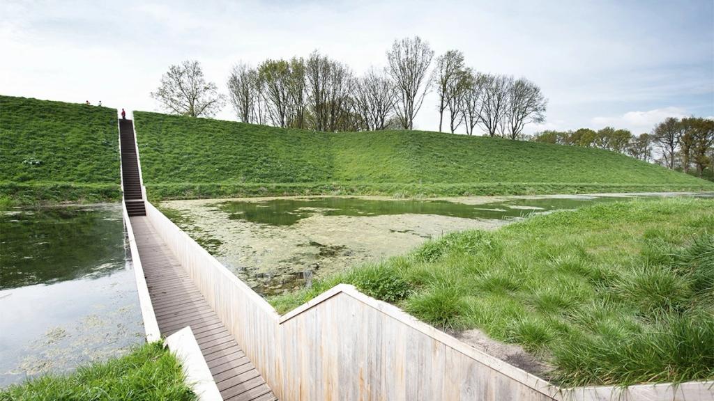 The Moses Bridge in the Netherlands: a timber passage cutting through the moat in front of a grassy fortress rampart