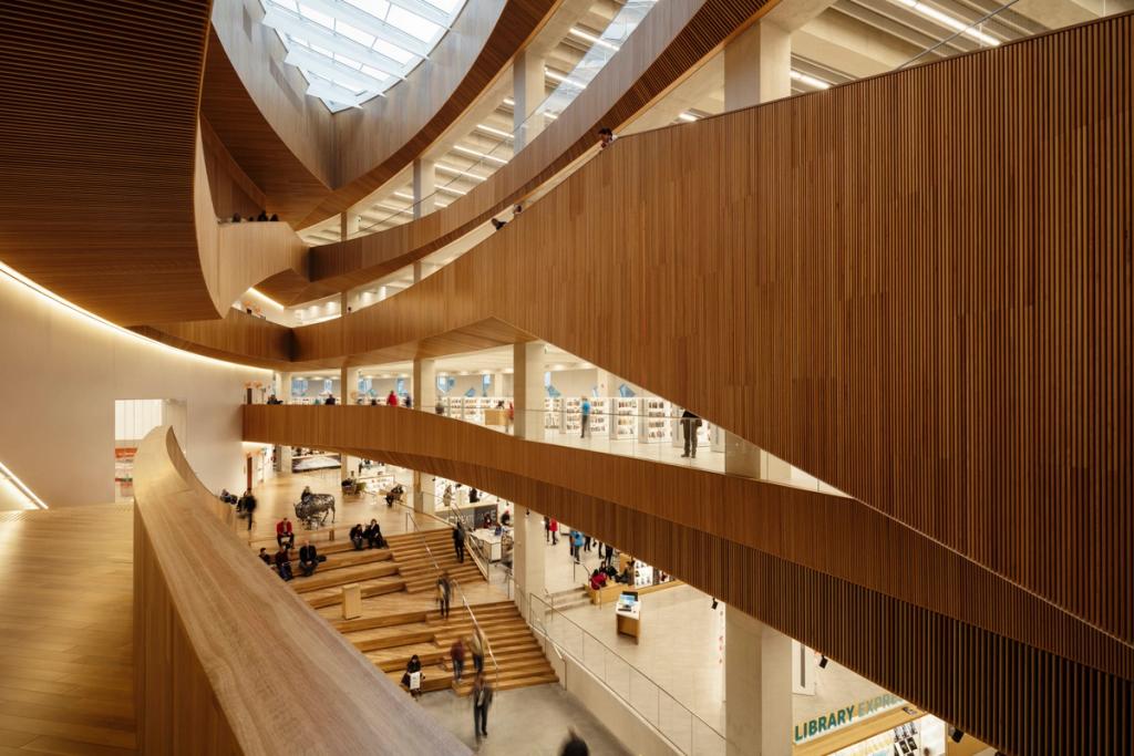 The multi-tiered wooden atrium of the Calgary library with curved balconies and a central staircase