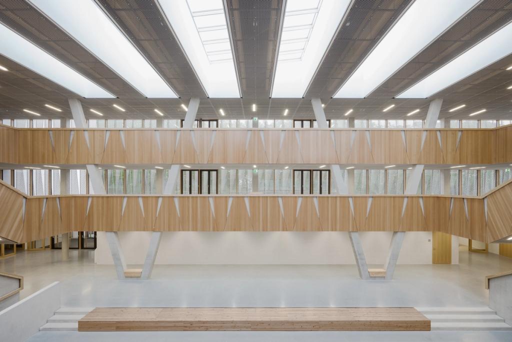 Hessenwald school: a wooden atrium with angled columns, galleries and overhead light