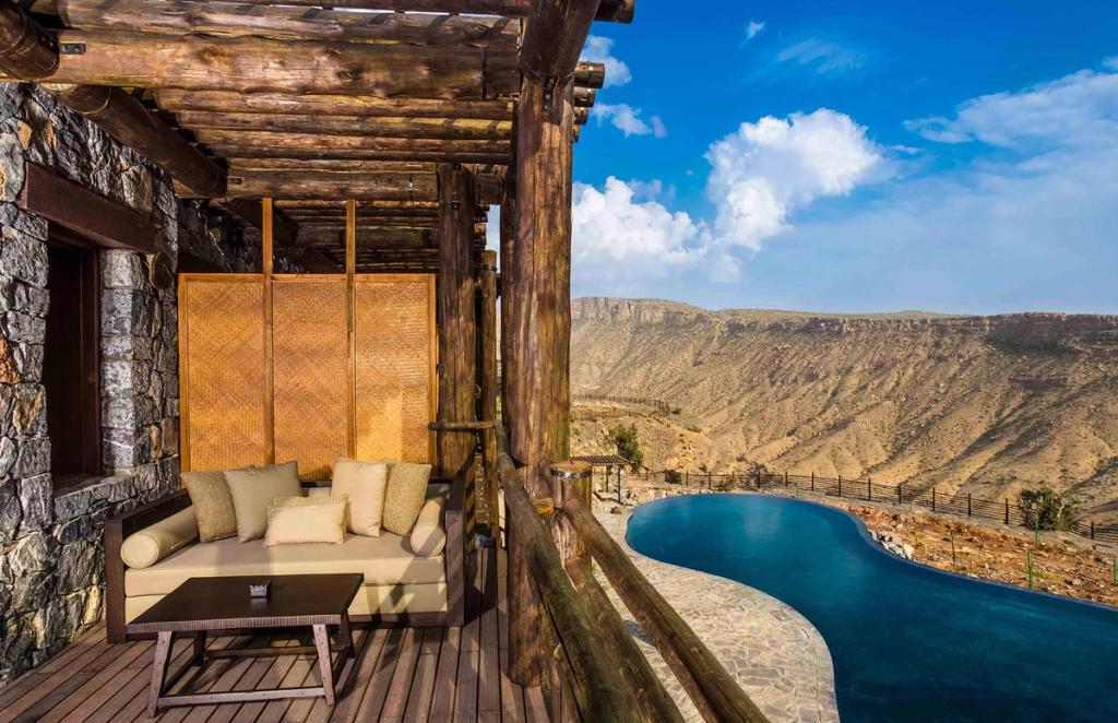 An Alila villa terrace with a sofa and pool on the edge of the Jebel Akhdar canyon